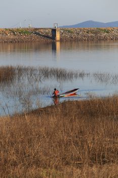 silhouette of fisherman on wood boat at lake.