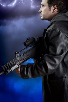 Man with long leather jacket and assault rifle over storm background