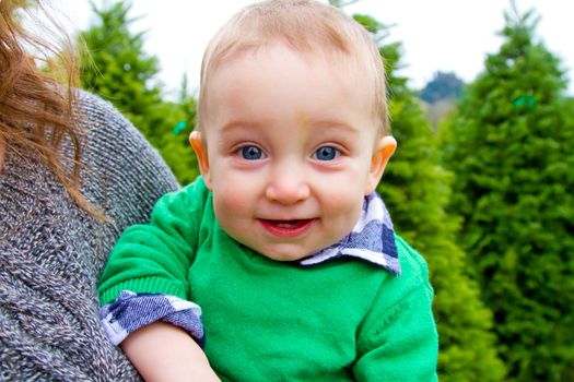 A cute young boy in a green shirt is having fun at a Christmas tree farm in Oregon.