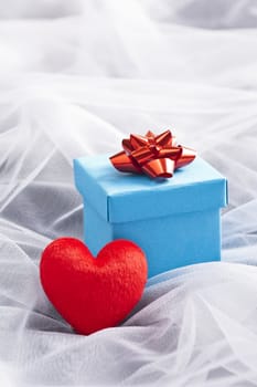 Blue Gift box with red bow on wedding veil with rose petals