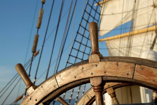 Wooden steering wheel against sails