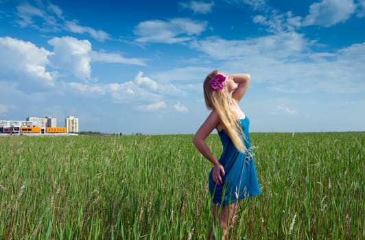 happy woman on green grass on background of the town buildings