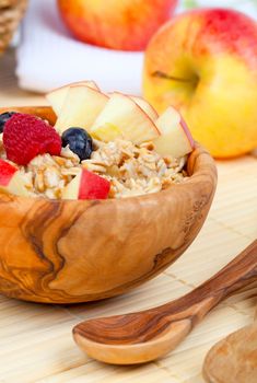 tasty oatmeal with raspberries and apple in the wooden bowl