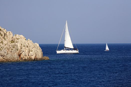 big and small sailing boats in the blue water of a greek island