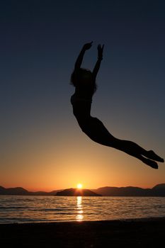 sunset and silhouette of a beautiful dancer in the beach