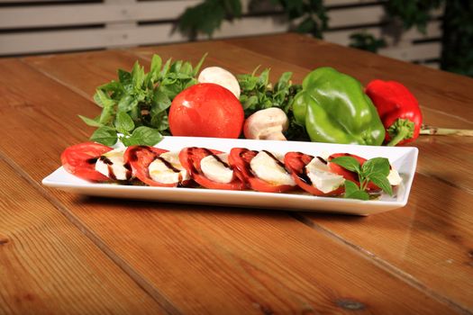 plate of a fresh tomato and mozarela cheese with pesto and balsamic