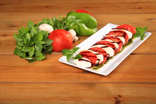 plate of a fresh tomato and mozarela cheese with pesto and balsamic