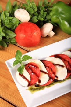 plate of a fresh tomato and mozarela cheese with pesto and balsamic