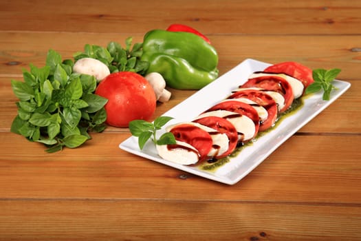 plate of a fresh tomato and mozarela cheese with pesto and balsamic