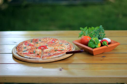 pizza and fresh vegetables served on a wooden table selective focus