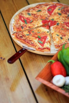 pizza and fresh vegetables served on a wooden table selective focus