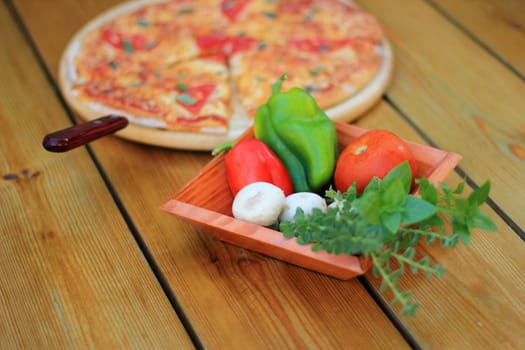 pizza and fresh vegetables served on a wooden table selective focus