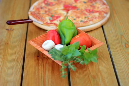 pizza and fresh vegetables served on a wooden table selective focus