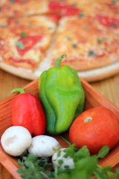 pizza and fresh vegetables served on a wooden table selective focus