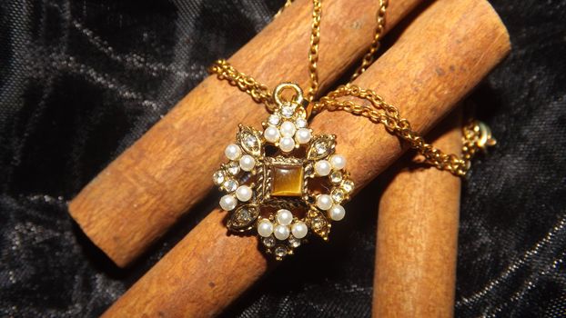 goldene Halskette mit Edelsteinen und einem Tigerauge in der Mitte.
a golden necklace with precious stone and a eye of tiger in the middle.