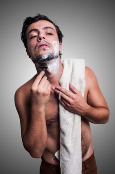 sexy man who shaves his beard on grey background