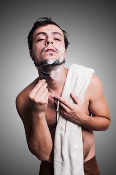 sexy man who shaves his beard on grey background