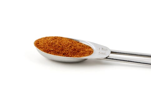 Chinese five spice measured in a metal teaspoon, isolated on a white background