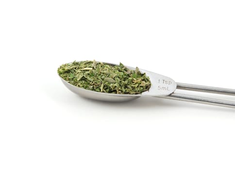 Mixed herbs measured in a metal teaspoon, isolated on a white background