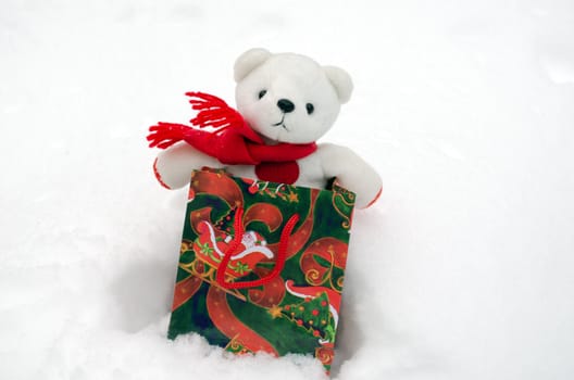 white plush teddy bear in christmas gift present bag on snow.