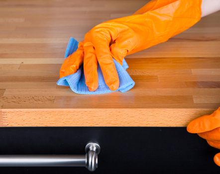 Rubber gloved hand cleaning table with duster