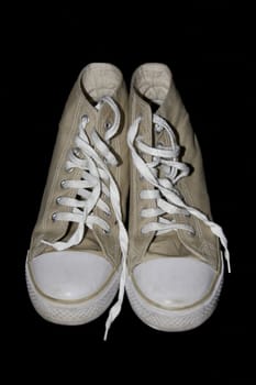 beige classic youth canvas shoes on a black background with a clipping path