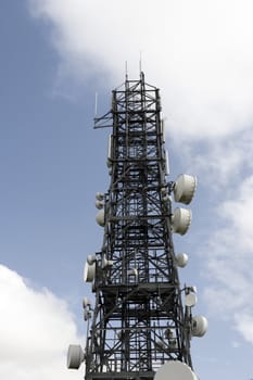a steel telecommunication tower with a cloudy sky background