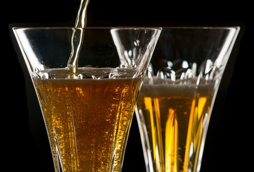 Detail of a pair of cut glass champagne goblet with a heart on the side and drink being poured