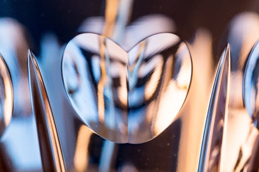 Detail of a cut glass champagne goblet with a heart on the side and drink being poured