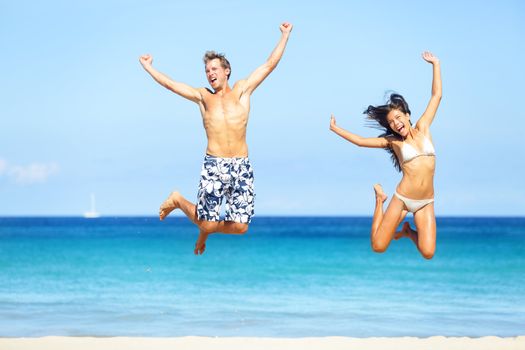 Beach people - happy couple jumping in swimwear and bikini. Sunny summer travel image with young multiethnic couple on Hawaii, Big Island. Caucasian man, Asian woman