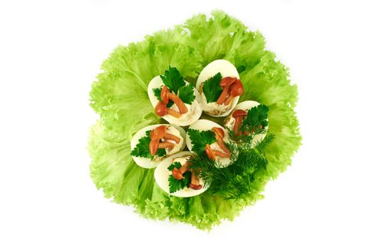 Cooked stuffed eggs decorated with pickled mushrooms on salad leaves