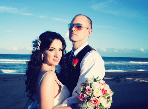 Bride and groom looking happy on the beach 