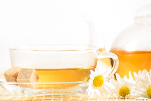 A teacup and a teapot with herbal chamomile tea