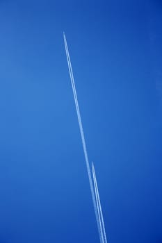 smoke lines from two airplanes in the blue sky