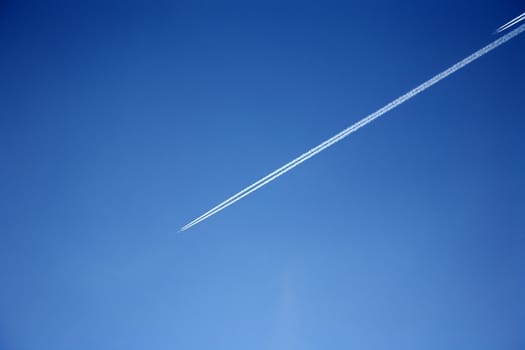 smoke lines from two airplanes in the blue sky