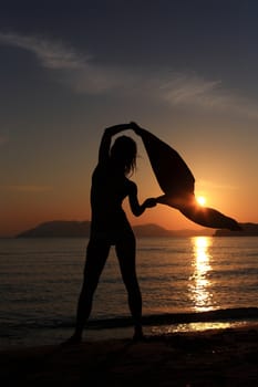 silhouette of a girl dancing in the beach with a beautiful sunset as a background