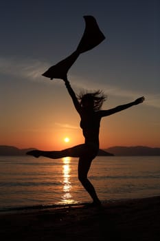 silhouette of a girl dancing in the beach with a beautiful sunset as a background