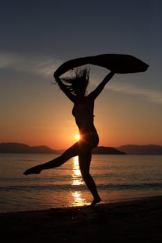 silhouette of a girl dancing in the beach with a beautiful sunset as a background