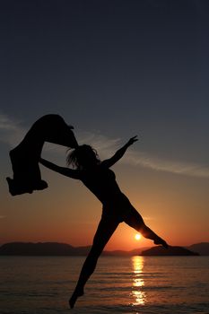 silhouette of a girl dancing in the beach with a beautiful sunset as a background