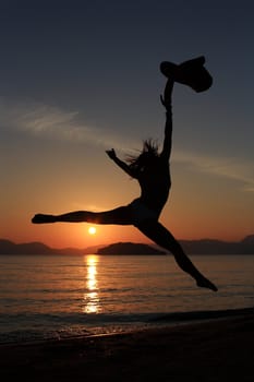 silhouette of a girl dancing in the beach with a beautiful sunset as a background