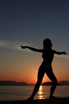 silhouette of a girl dancing in the beach with a beautiful sunset as a background