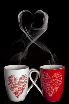 2 coffee cups with hearts creating smoke in shape of a heart on a black background
