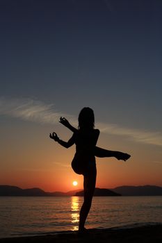 silhouette of a girl dancing in the beach with a beautiful sunset as a background