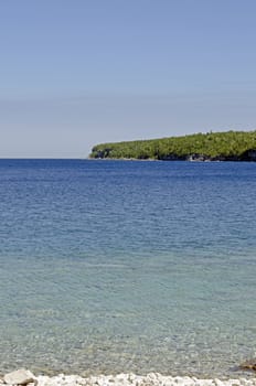 Green and blue water of Huron Lake, Ontario under blue sky.