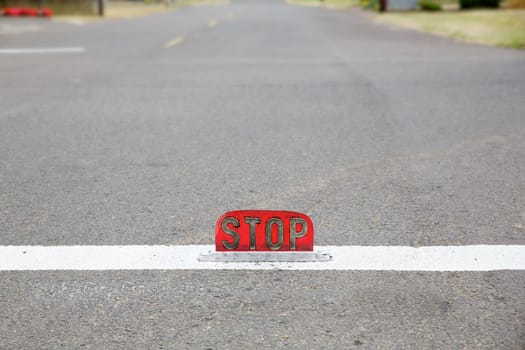 Old style street level stop signattached to center of the lane on a road