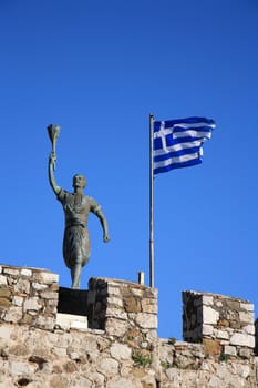 old statue and the greek flag in naypaktos greece