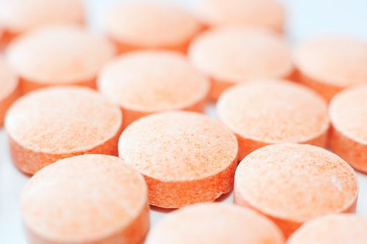 Macro of orange pills on white background