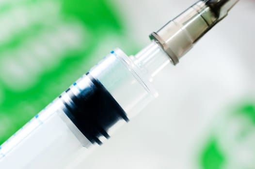 Syringe with needle on blur green background