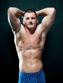 strong athletic man on black background looking at camera