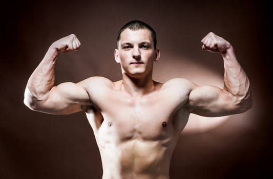Handsome muscular man over brown background